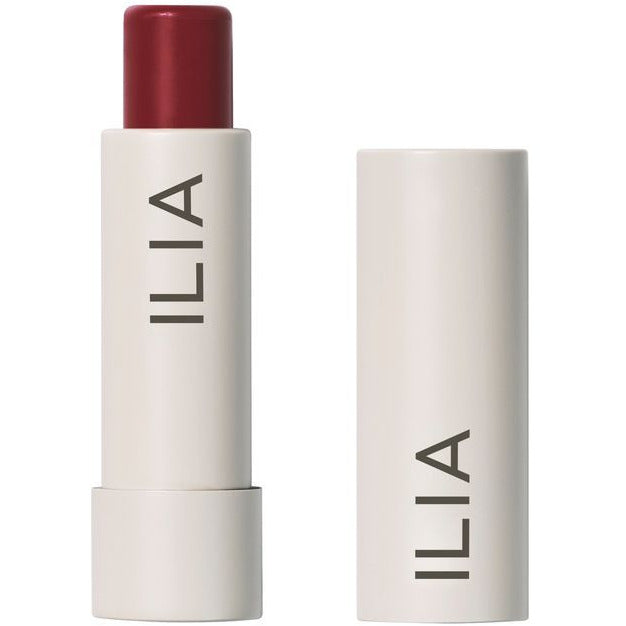 A red lipstick by ilia with its cap placed to the side.