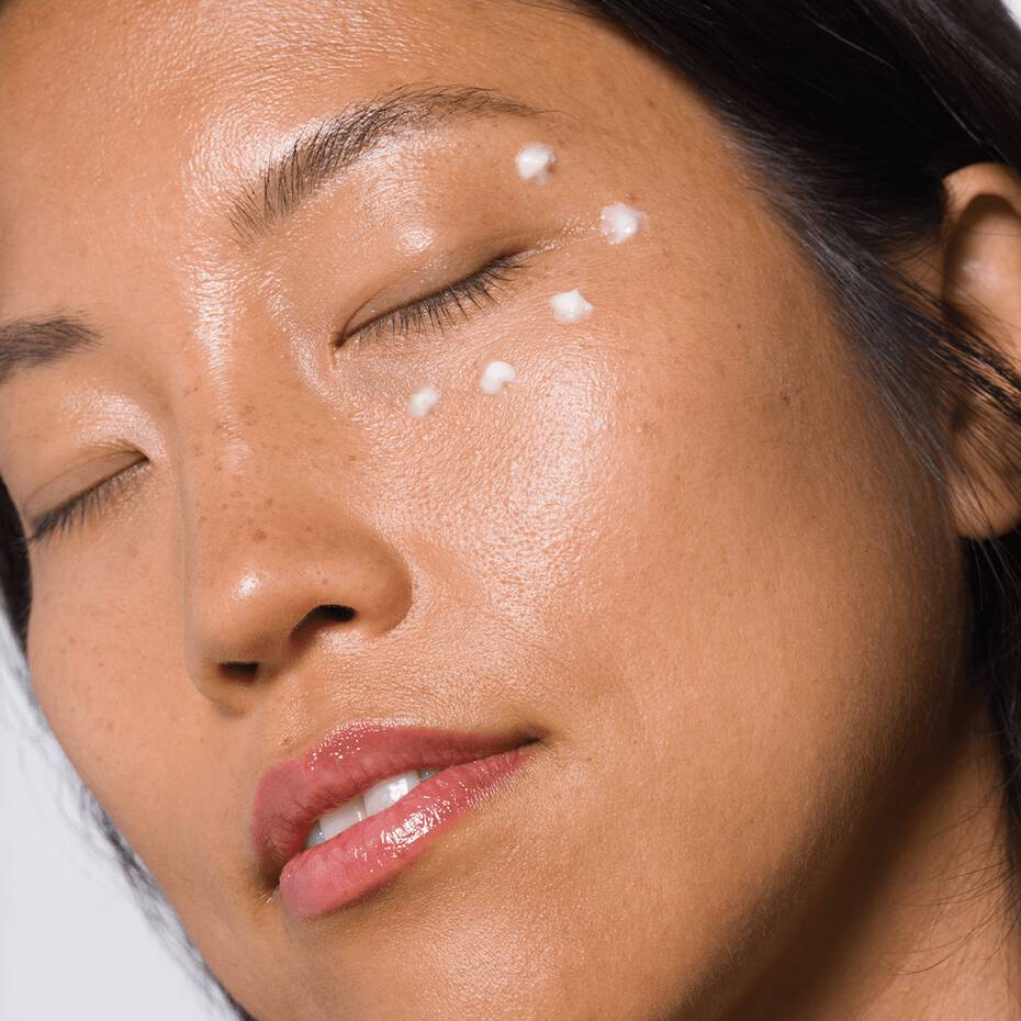 Close-up of a woman with dots of face cream on her cheek.