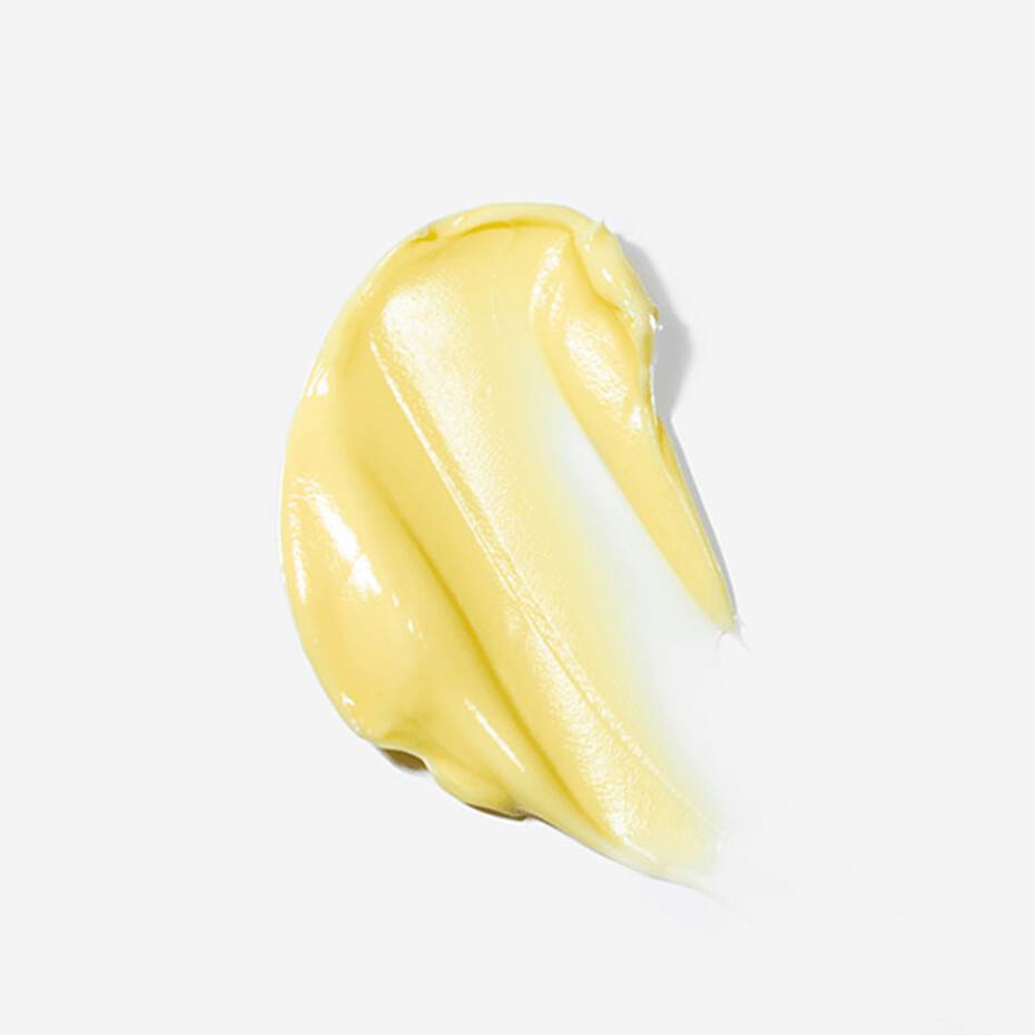 Dollop of yellow cream smeared on a white background.