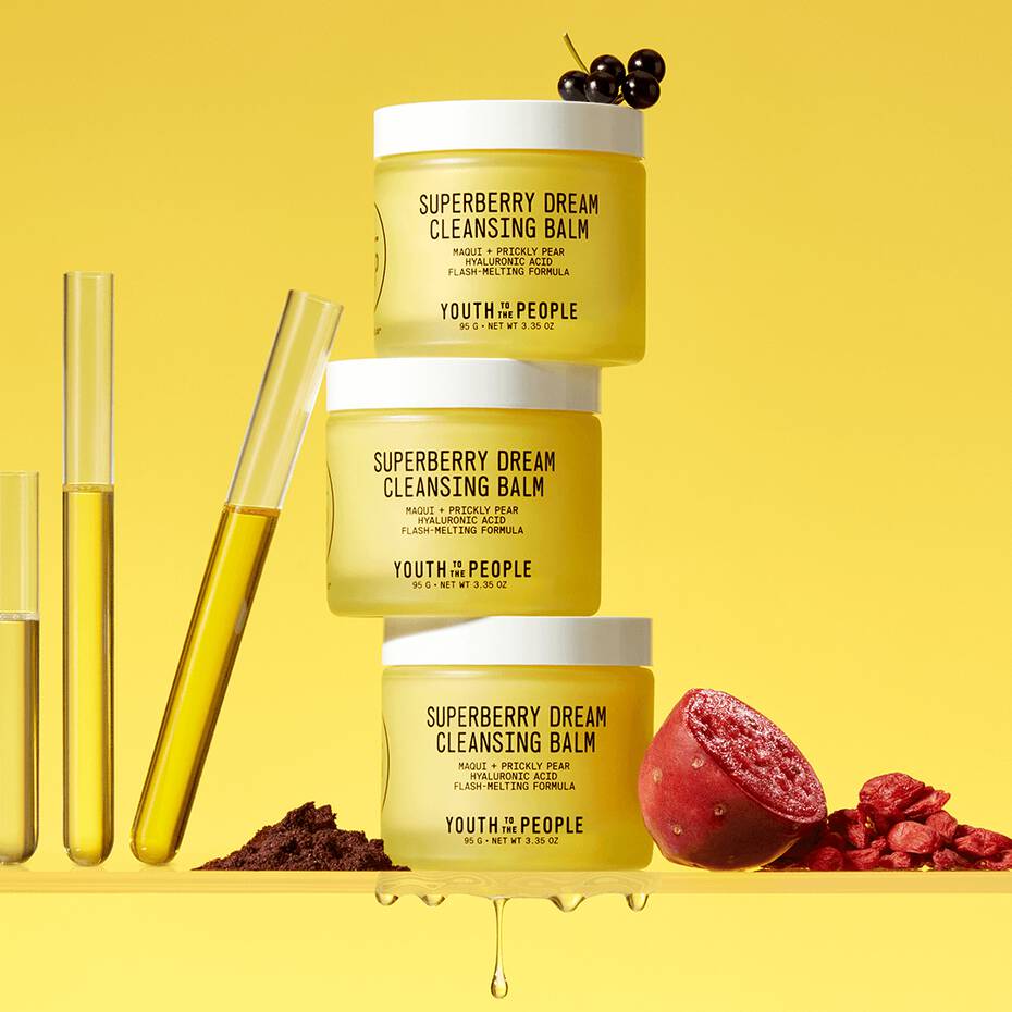 Stack of skincare products with ingredients displayed on a yellow background.